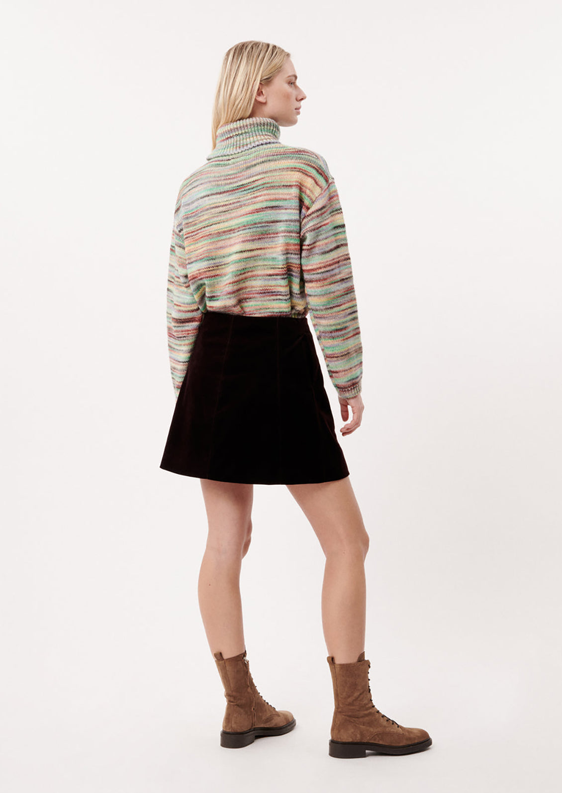 A woman wearing a turtleneck sweater in multicolor spacedye knit.