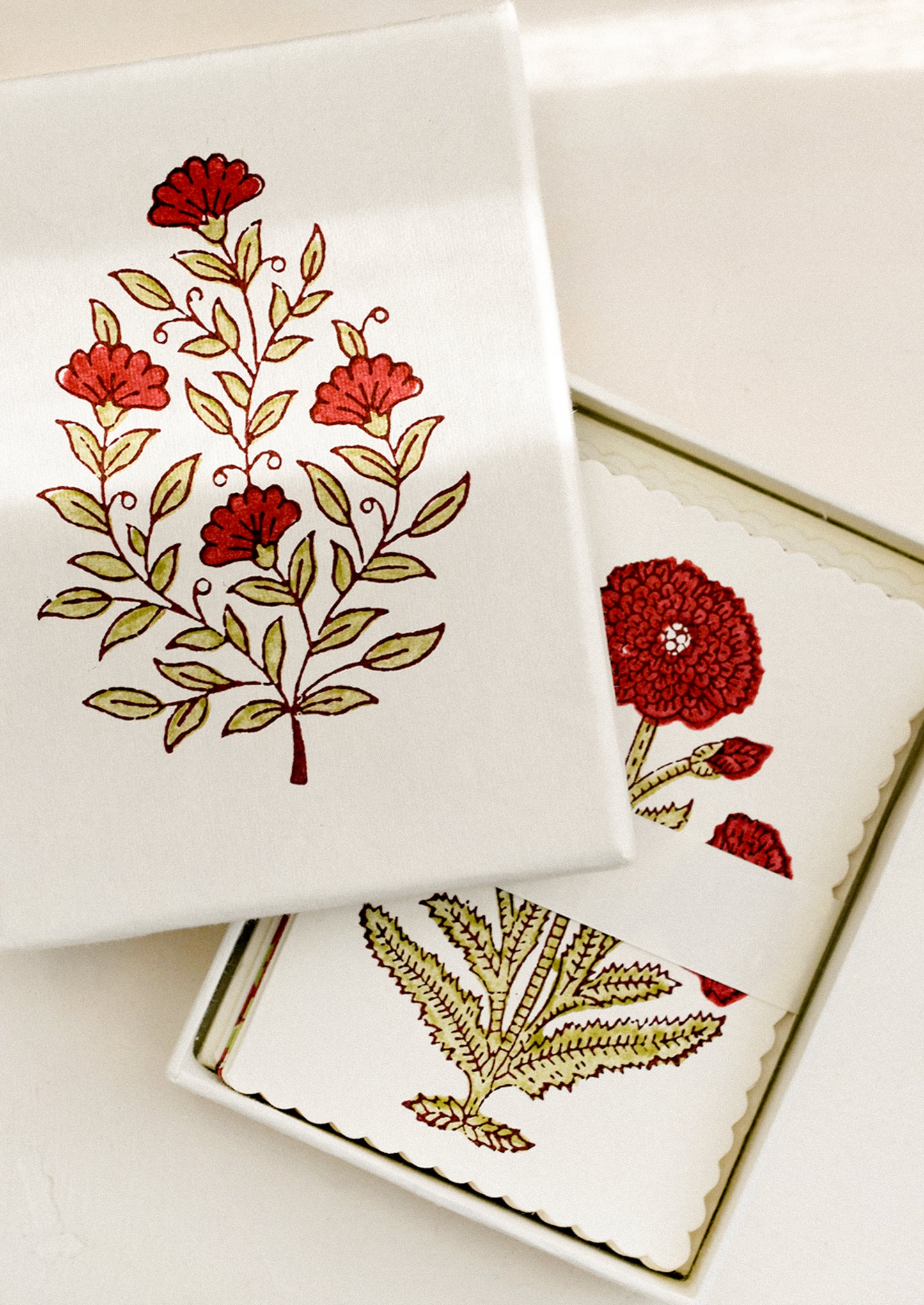 A set of red floral print, scalloped edge notecards in matching floral gift box.