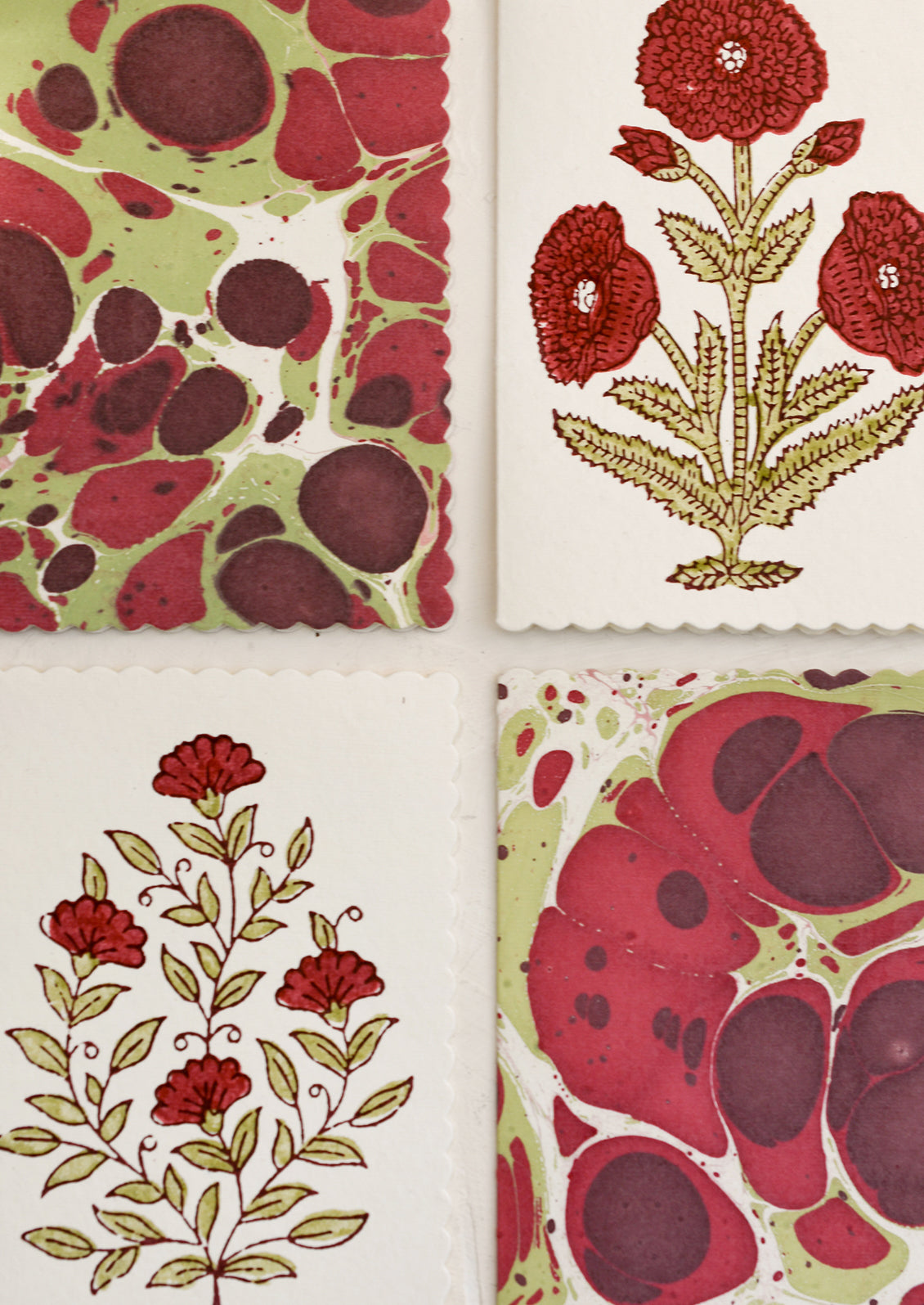 A set of assorted red and green floral print and marbleized notecards.