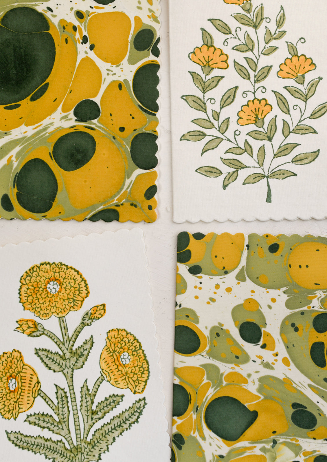A set of assorted yellow and green floral print and marbleized notecards.
