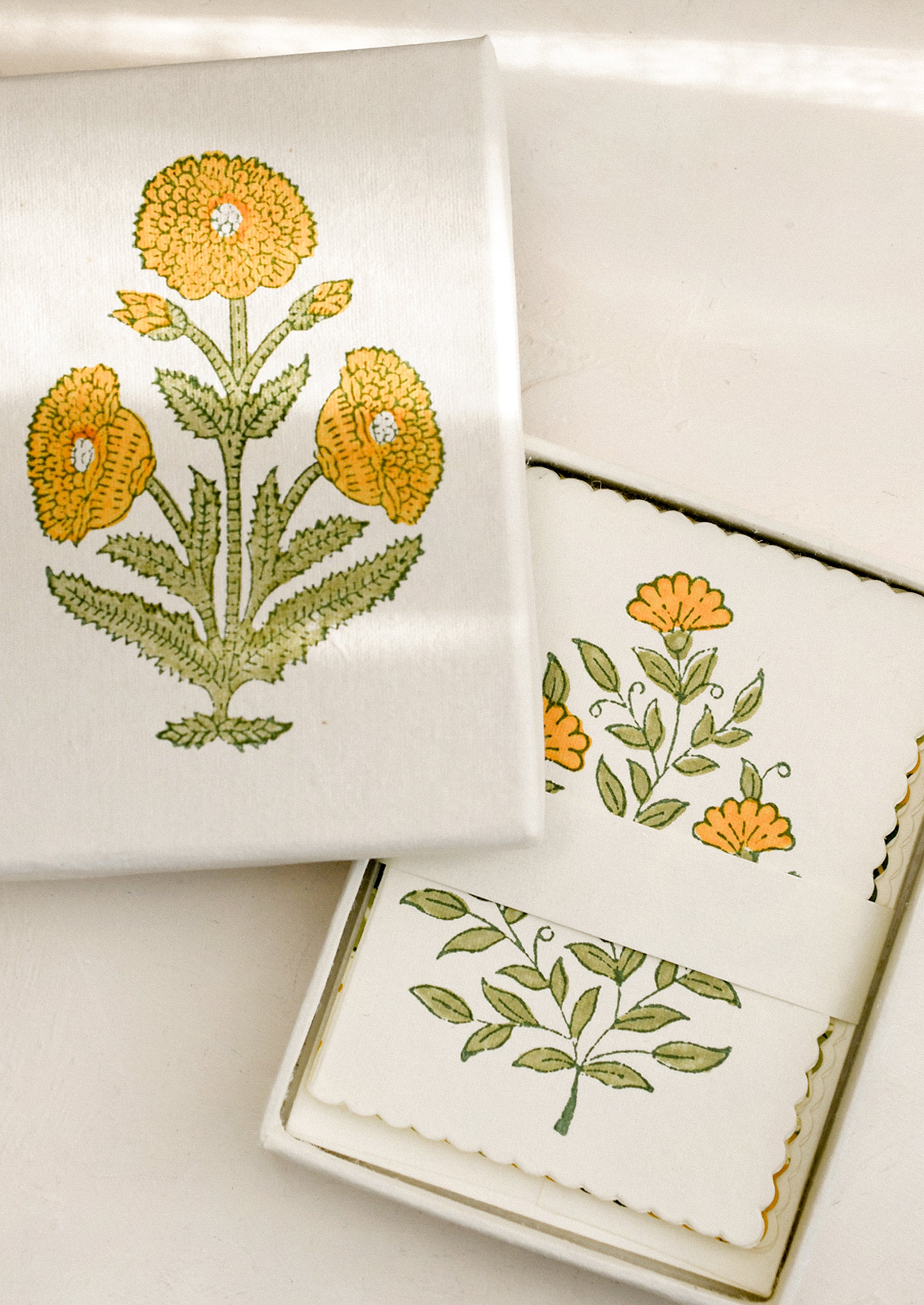 A set of yellow floral print, scalloped edge notecards in matching floral gift box.