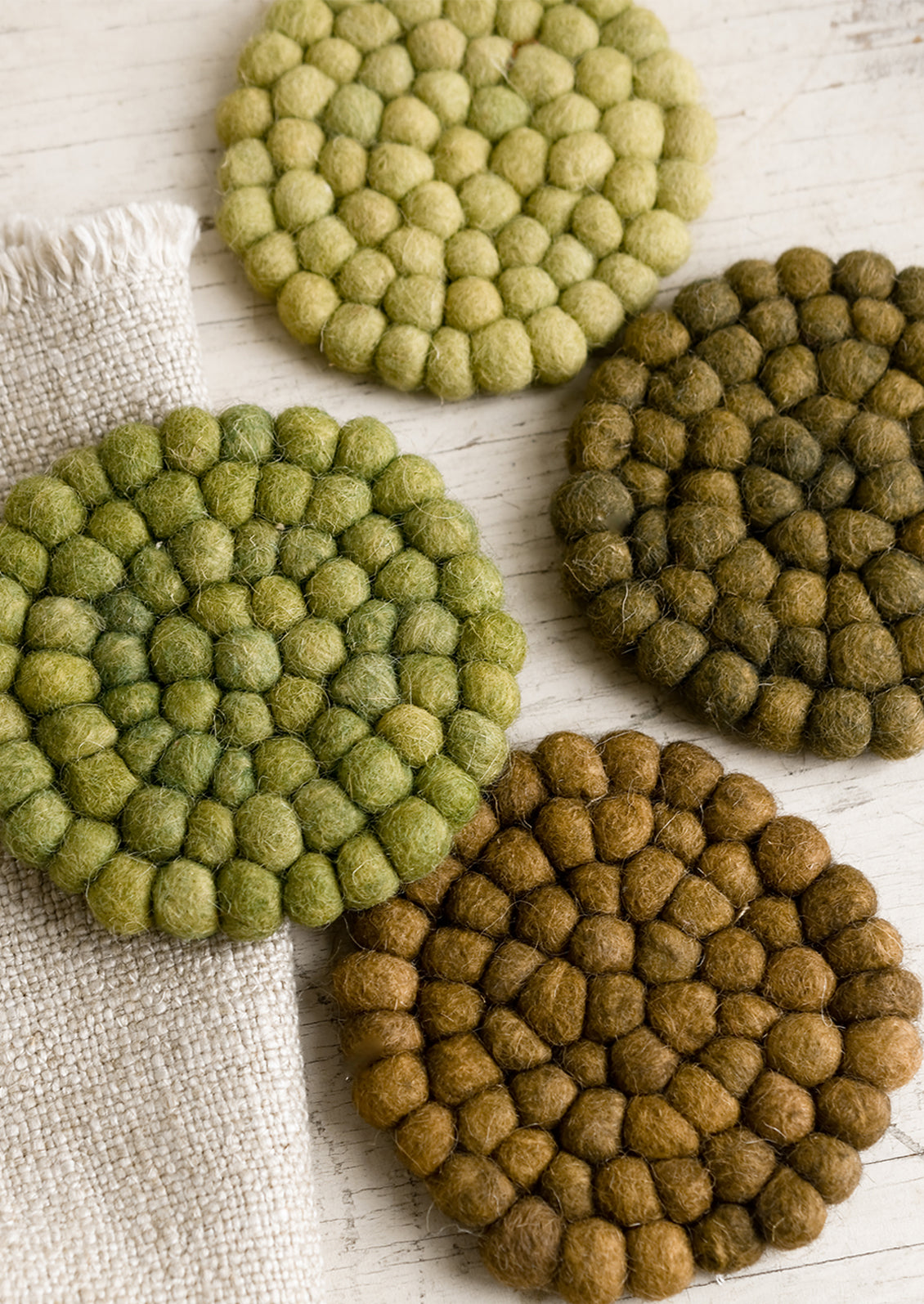 A set of felted ball coasters in mixed tones of green.