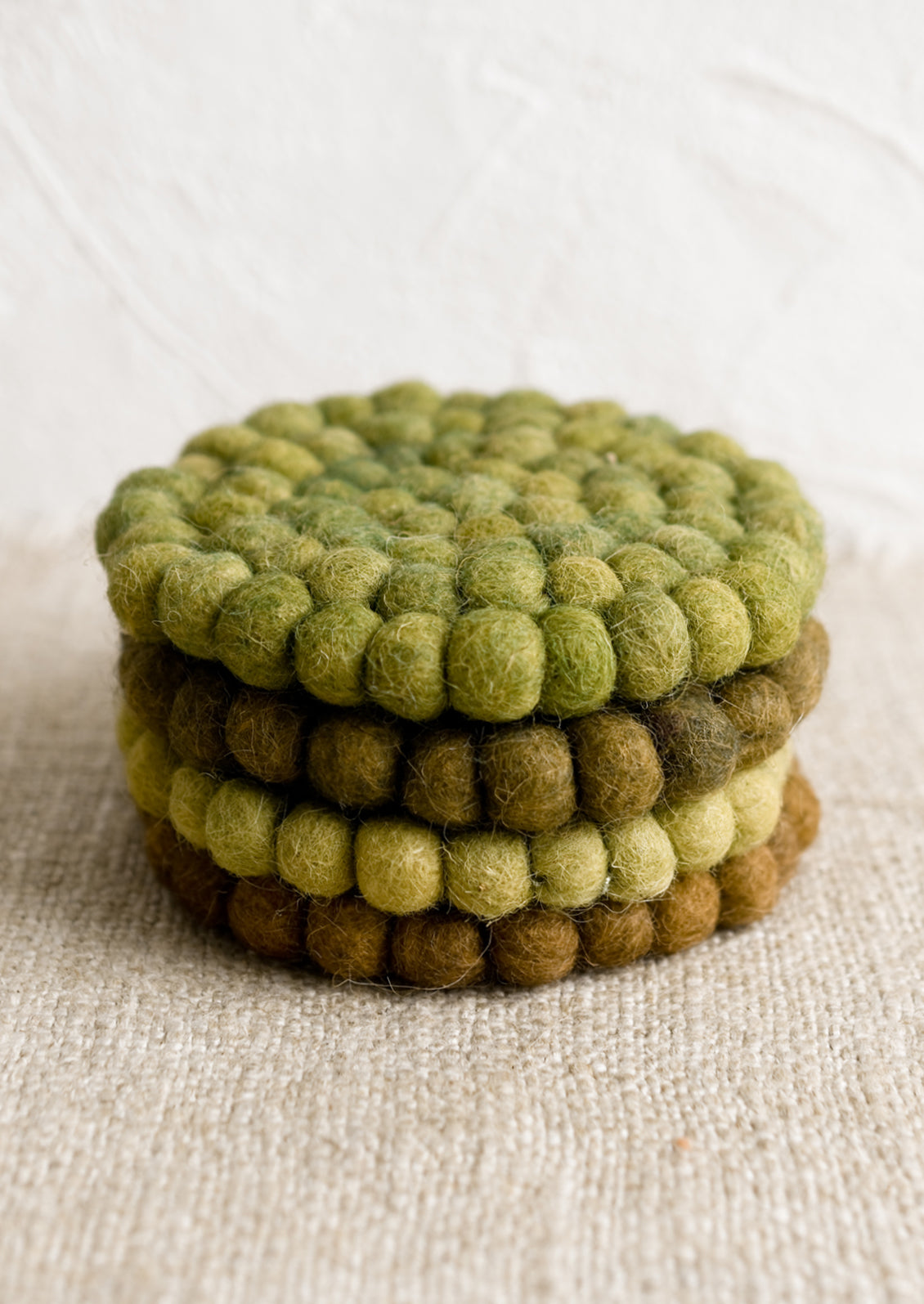 A set of felted ball coasters in mixed tones of green.
