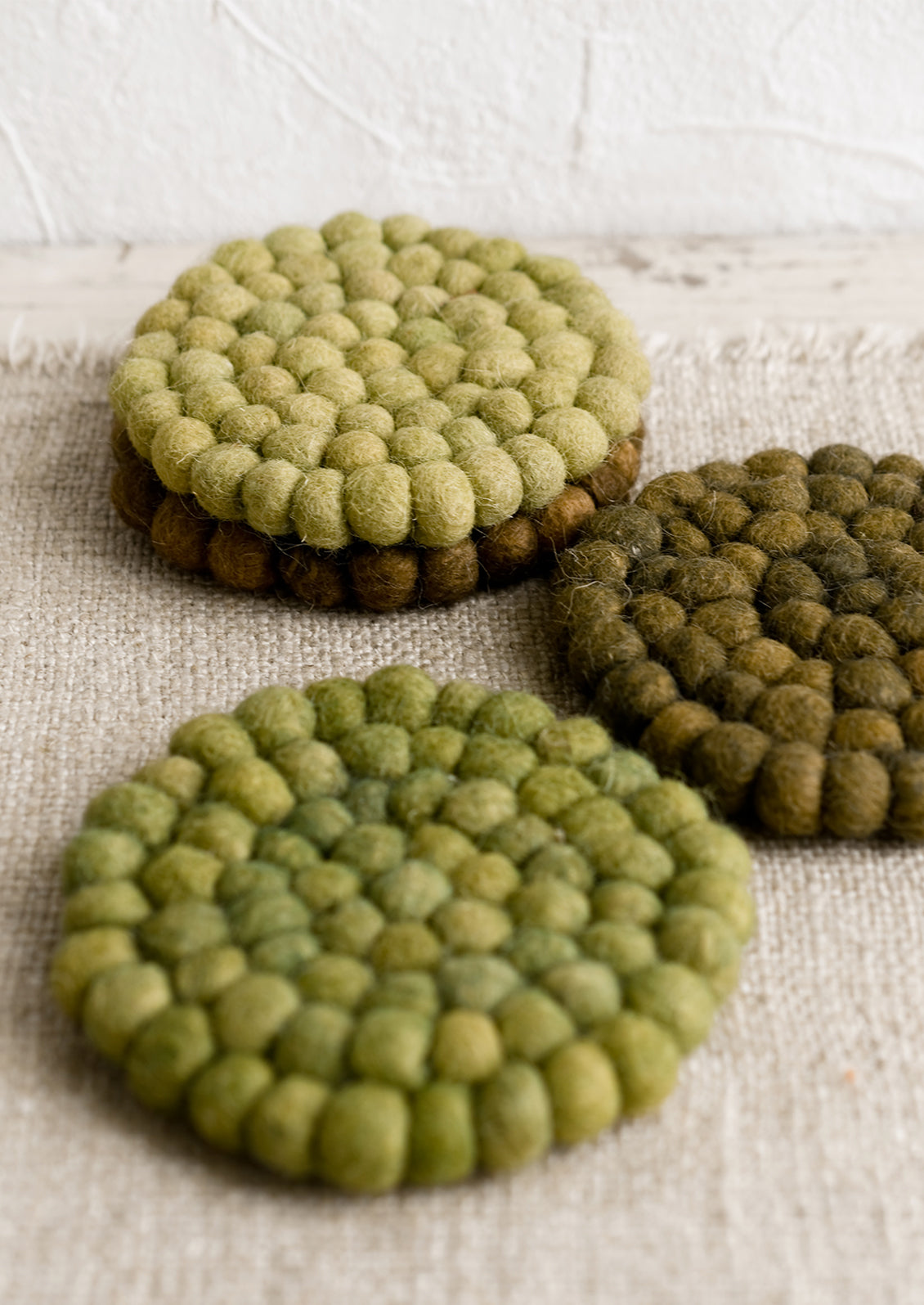 A set of felted ball coasters in mixed tones of green.