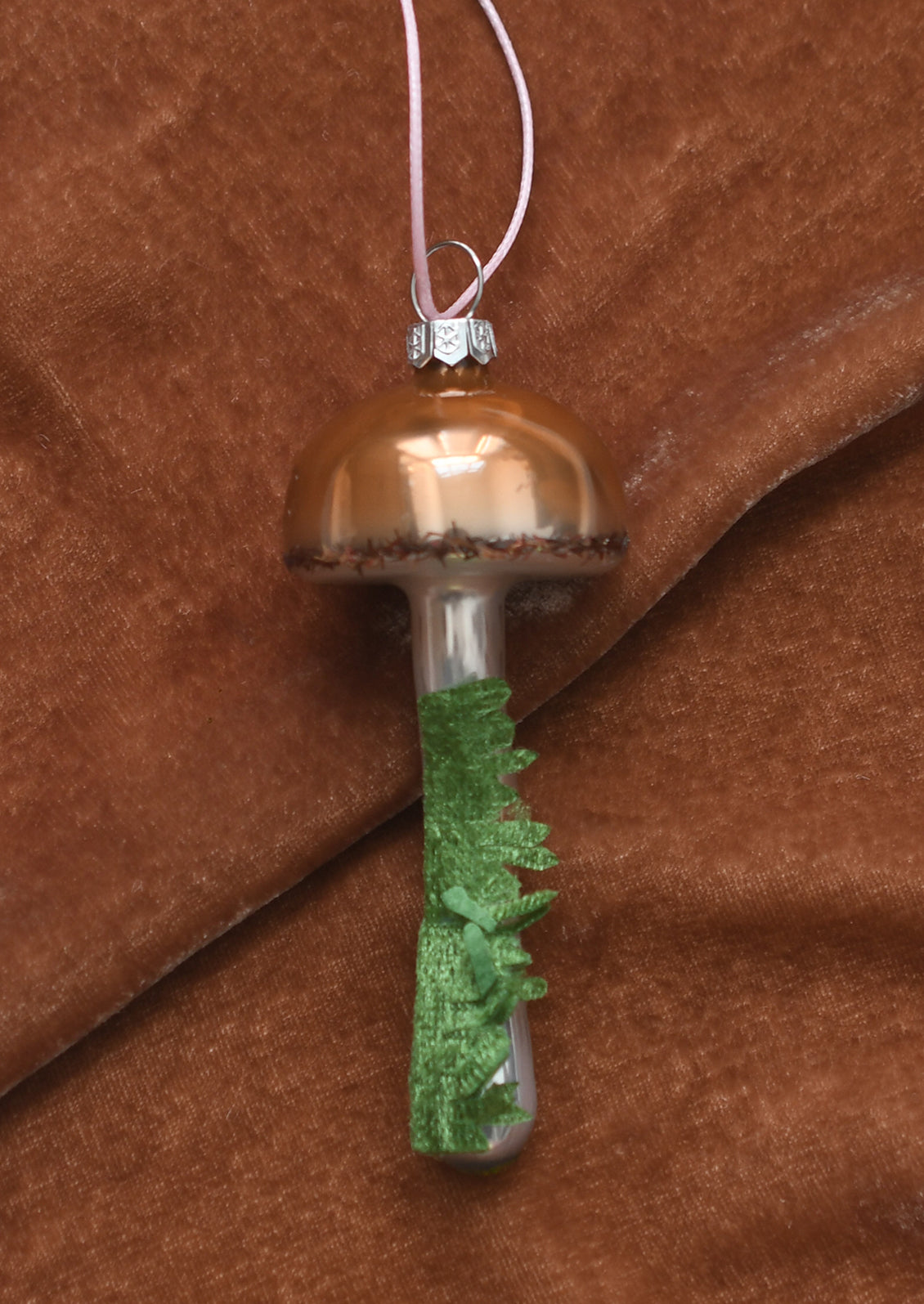 A glass ornament resembling a button mushroom with moss detail.