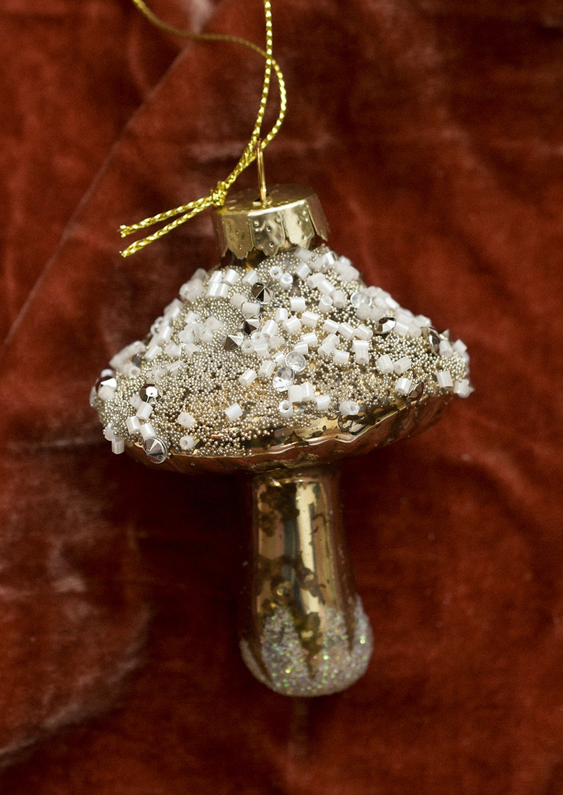 A glass ornament of gold mushroom with beaded "snow".