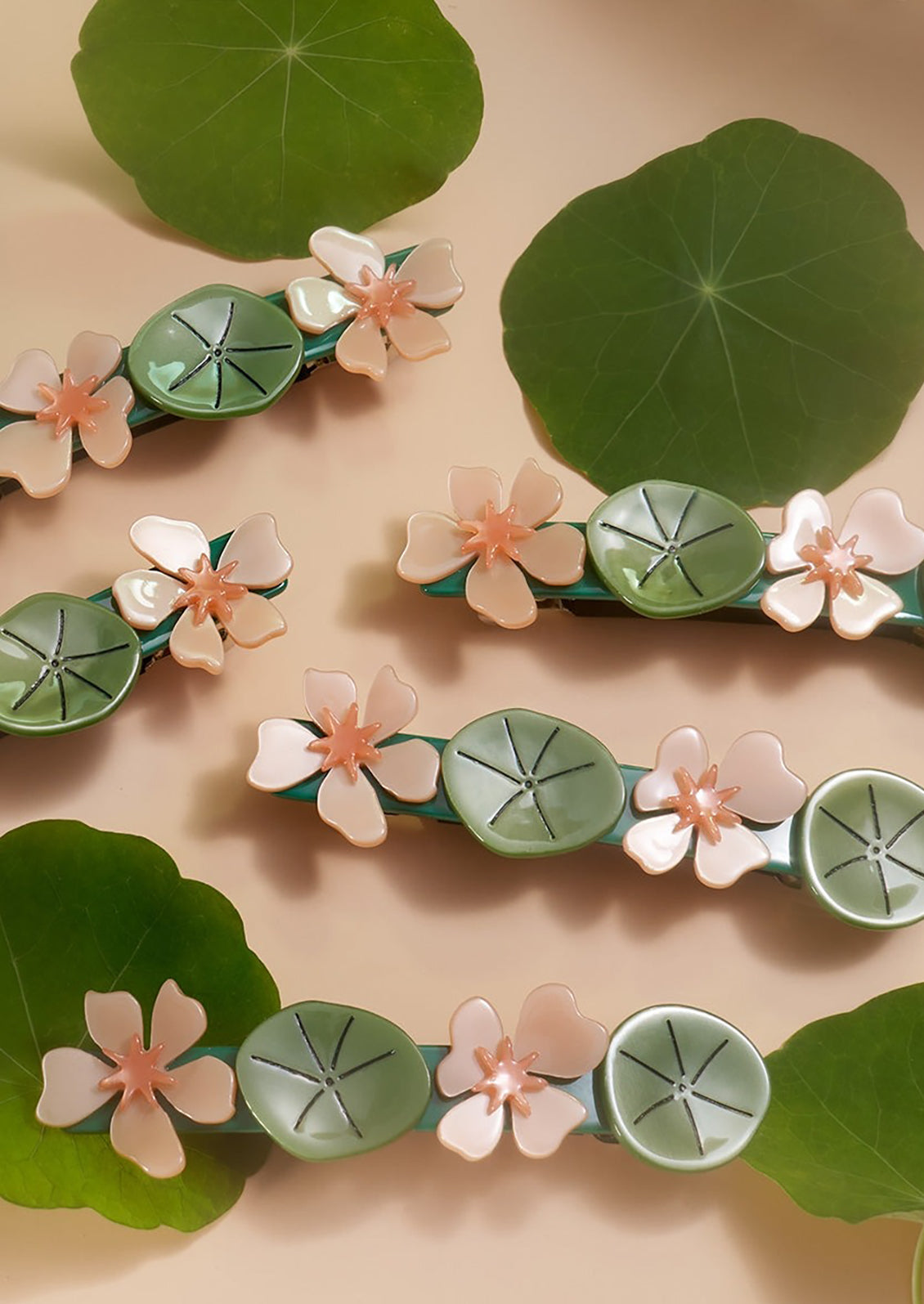 A selection of barrettes with green and pink floral designs and a green leaf background.