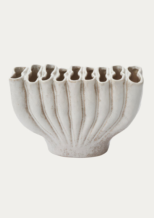 A fluted ceramic vase with east-west orientation and slot-like openings at top.