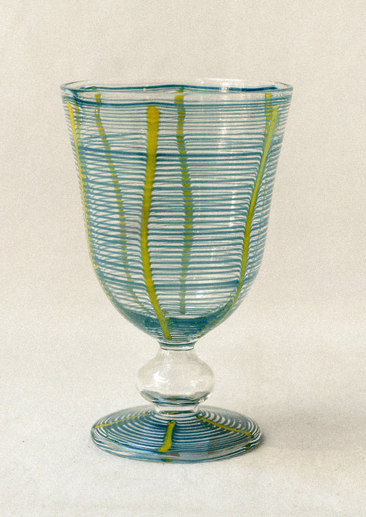 Decorative glass goblet with blue and green striped pattern on a white background