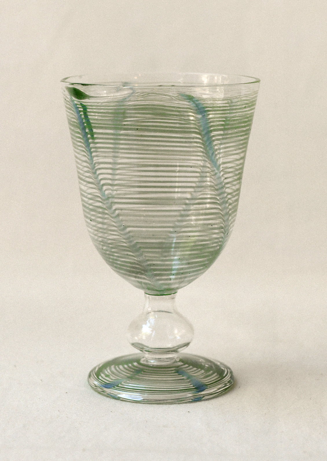 Green ribbed glass goblet on a light background