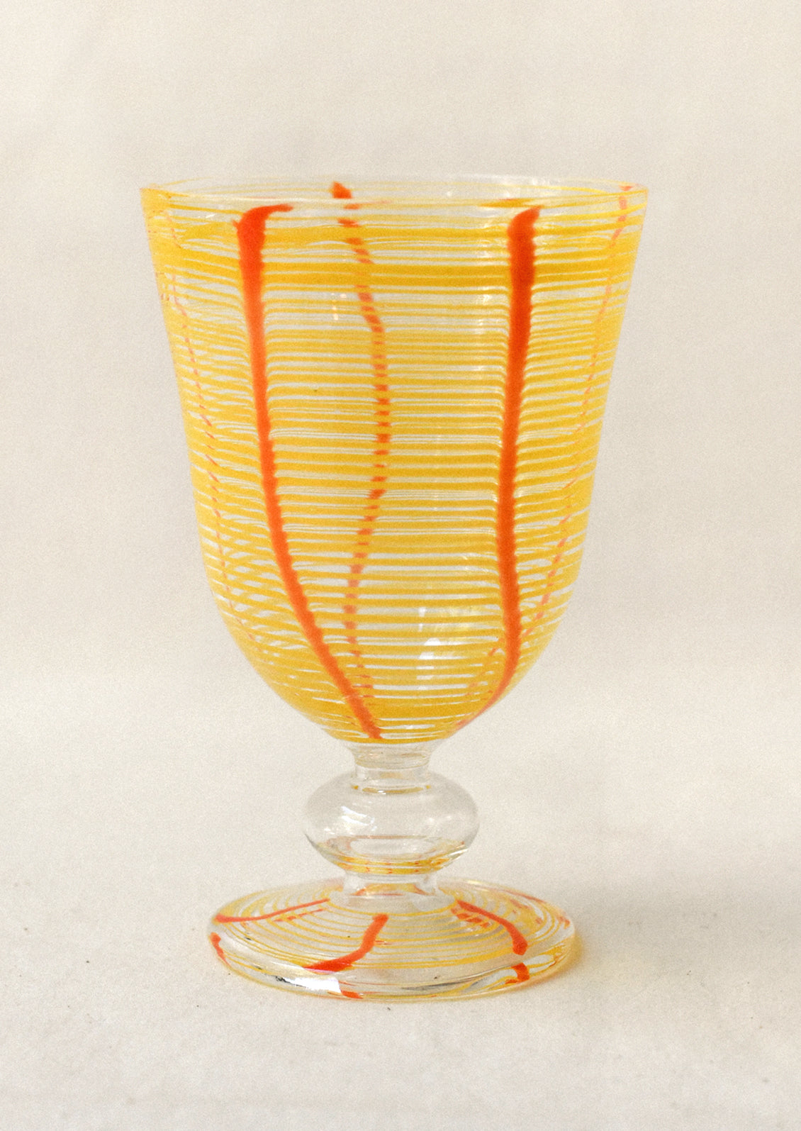 Glass with orange and yellow ribbed design on a white background