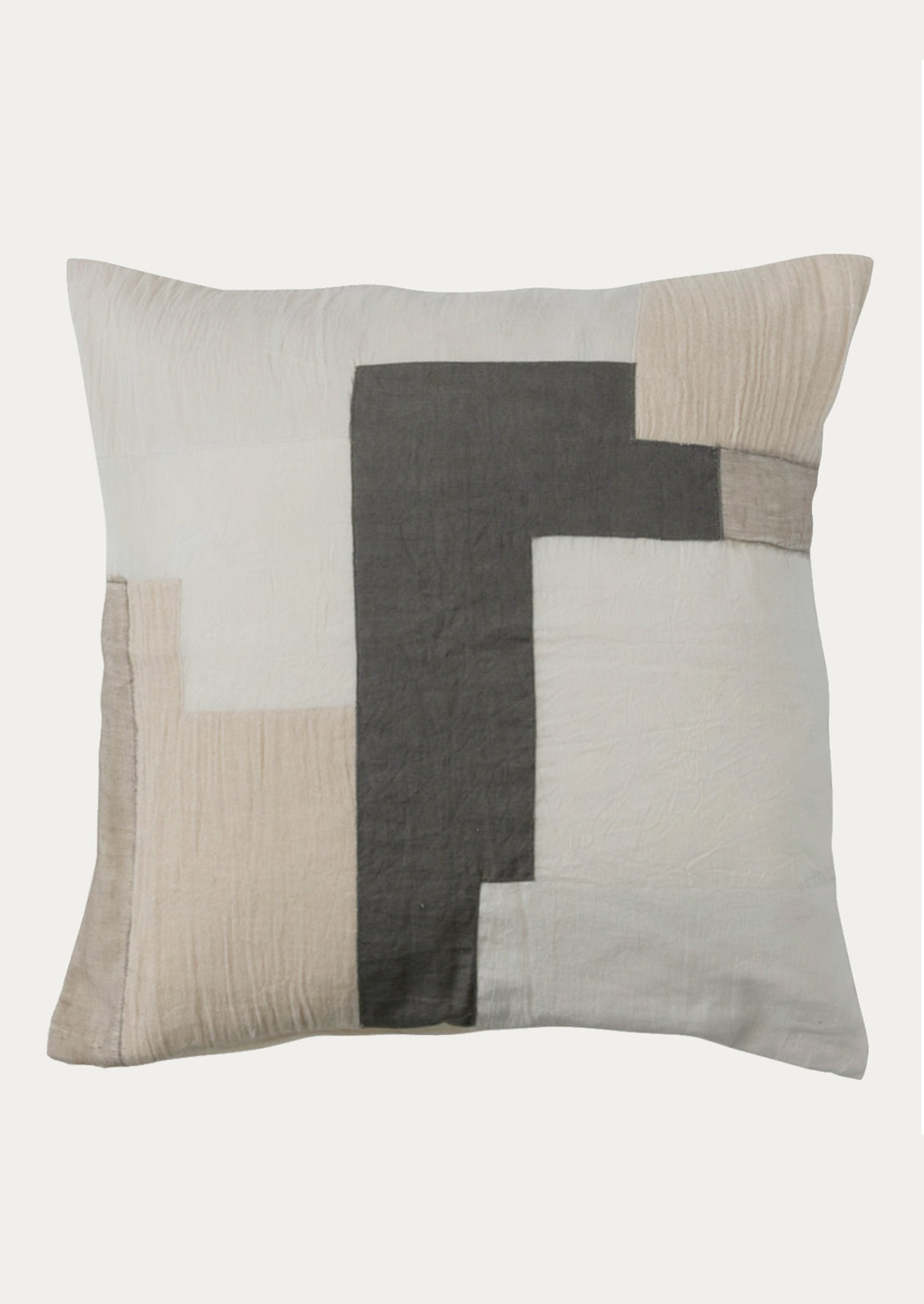 A throw pillow in sheer linen material with patchwork design in neutral colors.