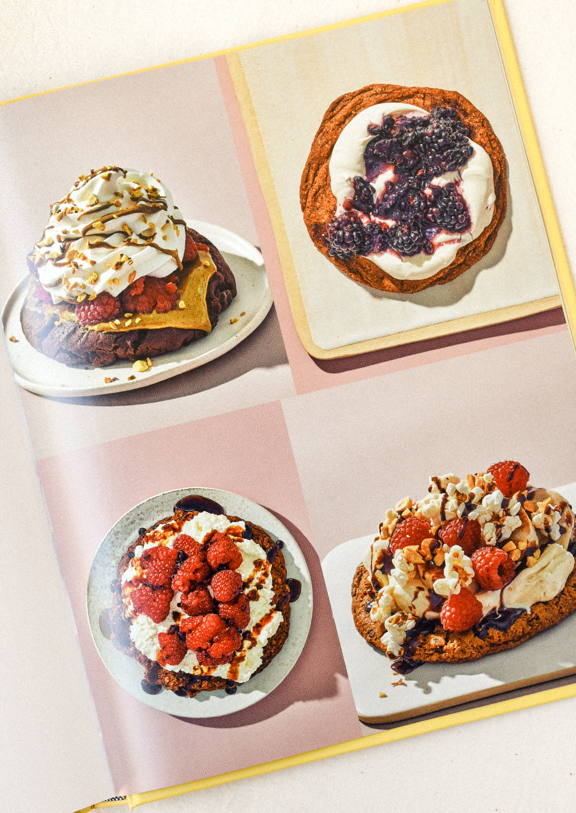 A cookbook open on a table with images of different types of desserts.