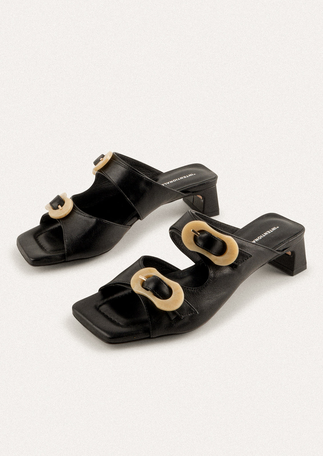 A square toe heeled sandal in black with double tan buckle detail.