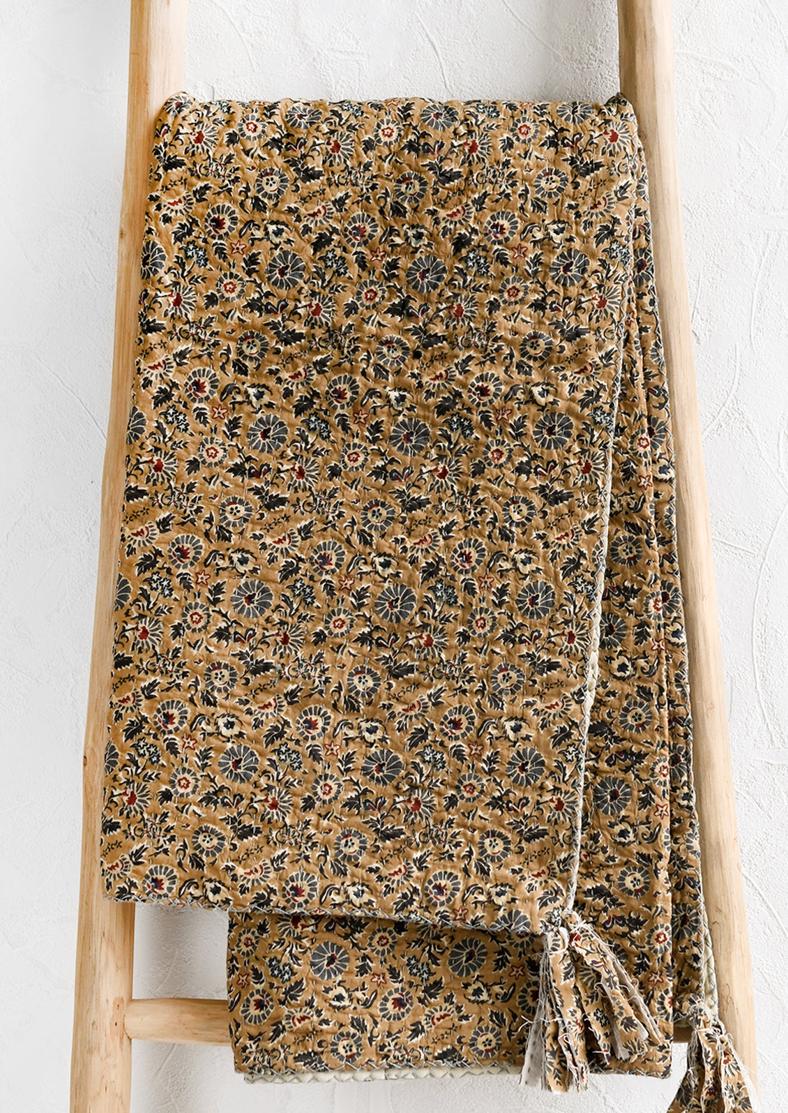A kantha stitched throw blanket with blue and brown floral print.