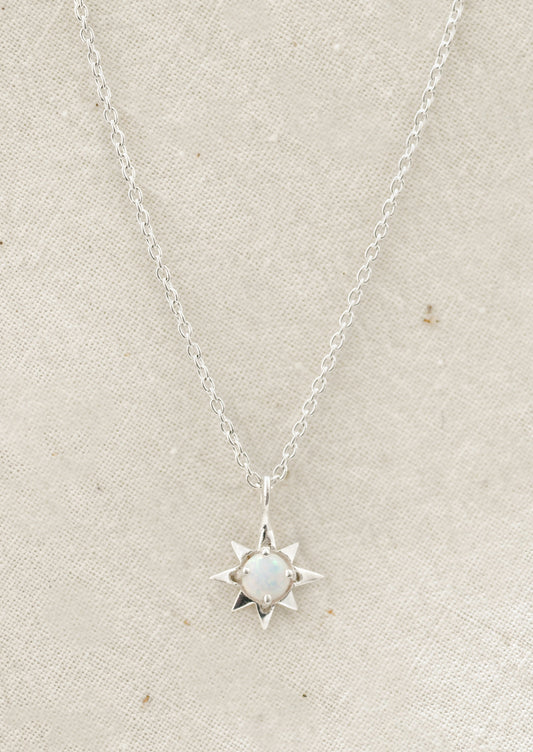 A sterling silver necklace with a north star shaped charm with an opal in the center.