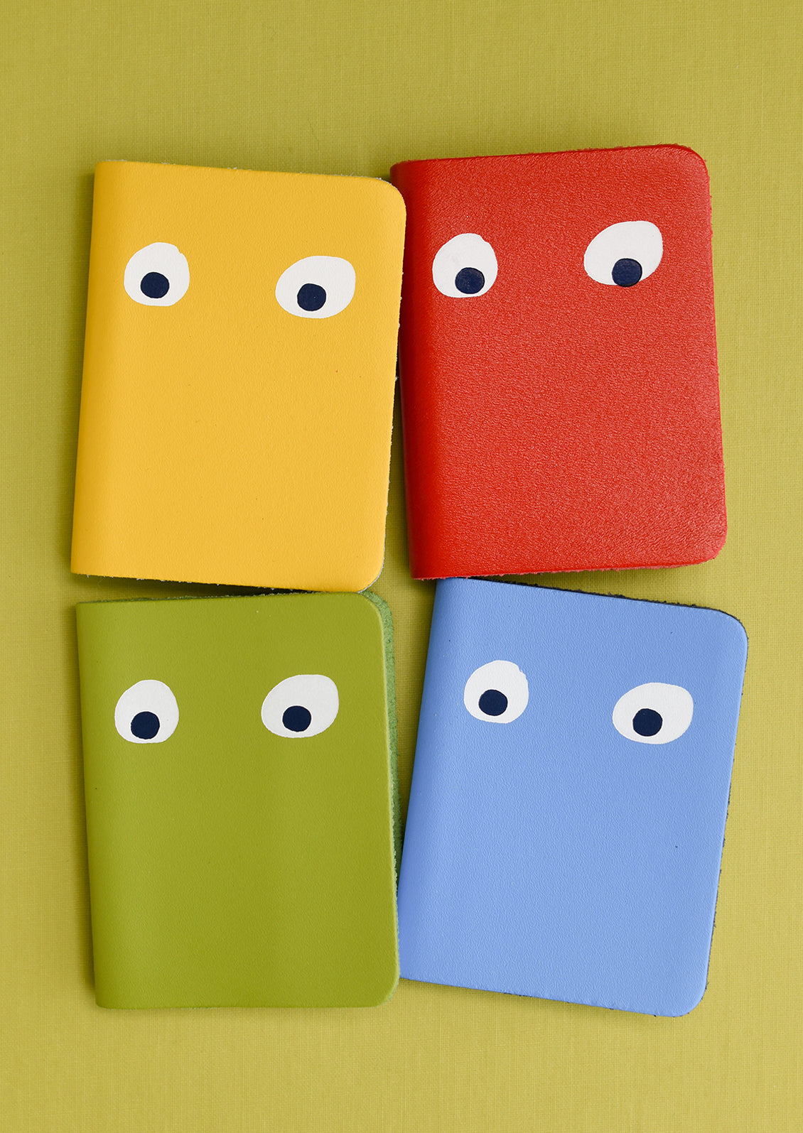 Four leather notebooks with pair of eyes painted on cover.