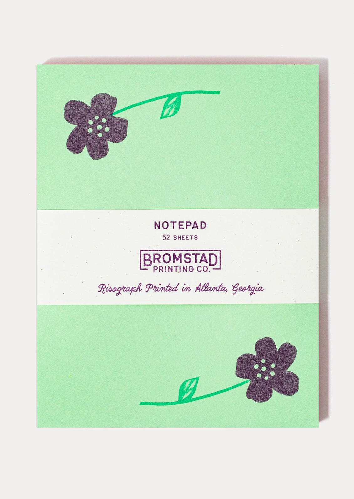 A green notepad with purple flower print at corners.