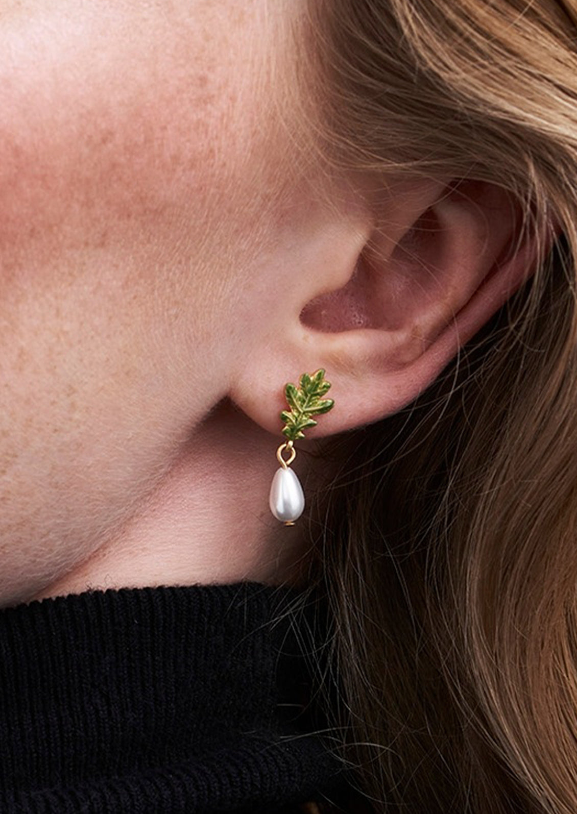 An oak leaf earring with a large pearl dangling at the end.