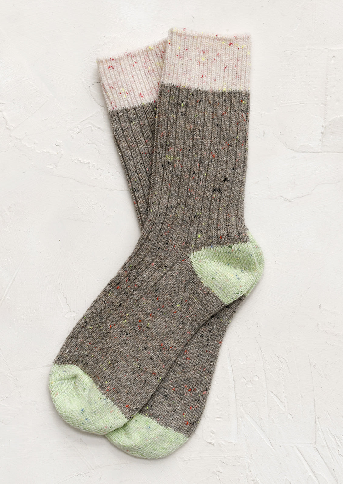 A pair of taupe socks with pink and green contrast.