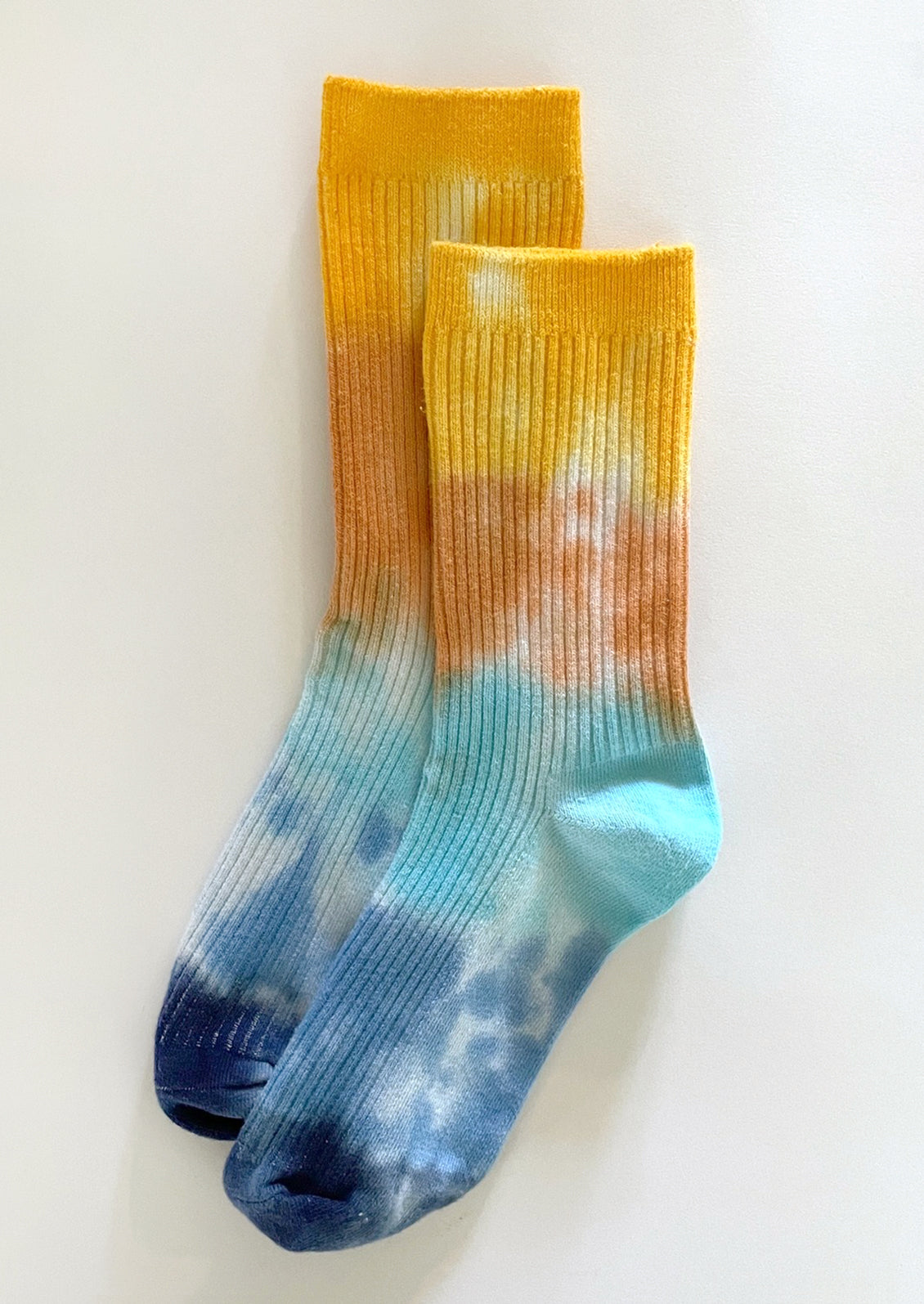 A pair of tie dye socks in yellow, orange and blue.