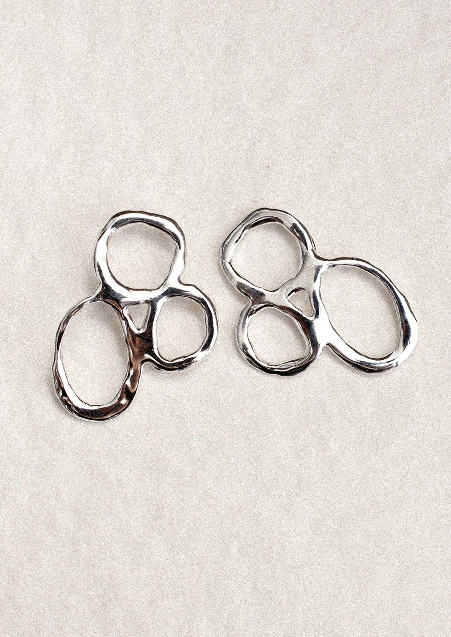 A pair of silver earrings with three organic circles melded together.