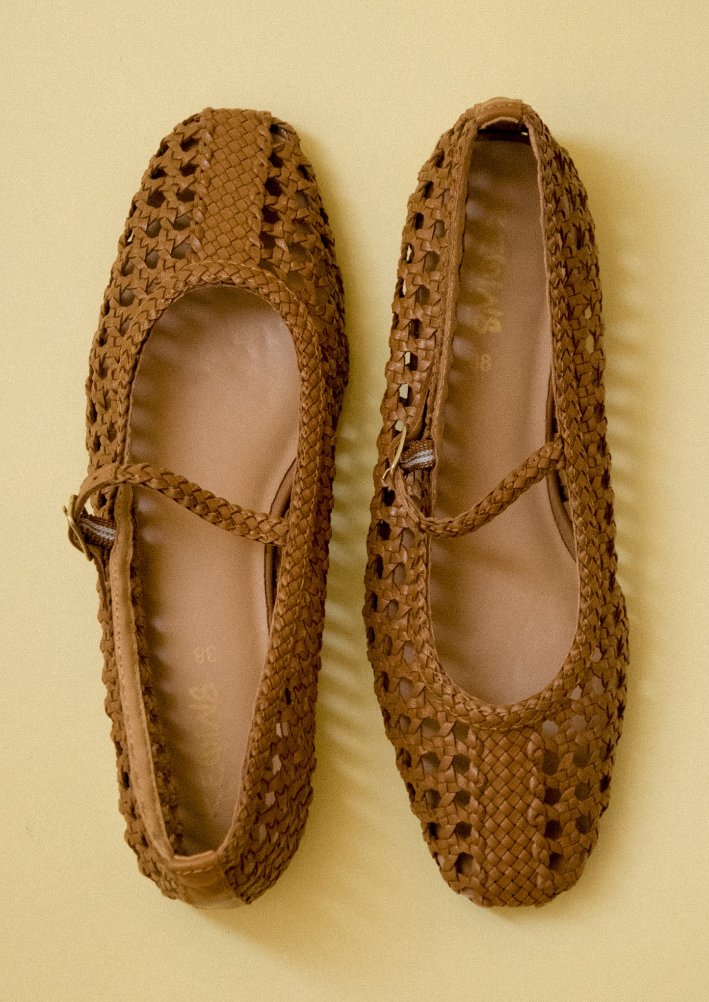 A pair of brown open weave ballet flats.
