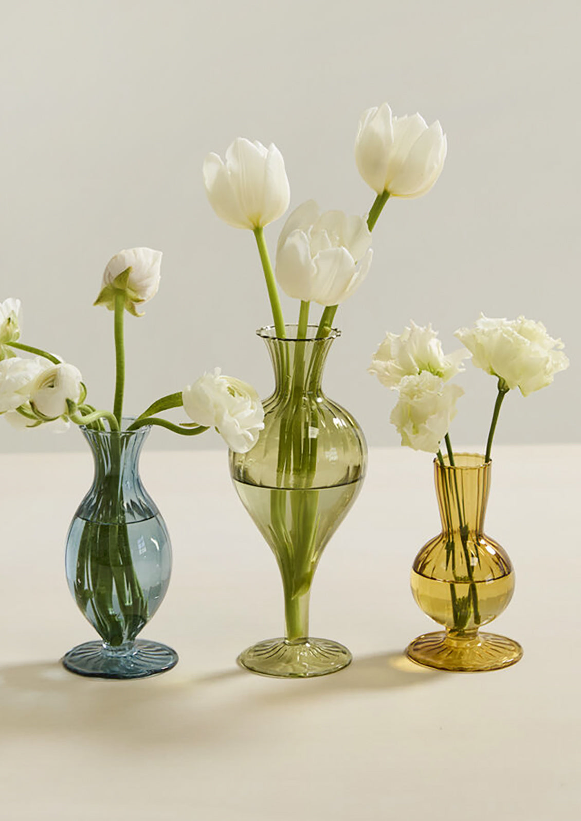 Three fluted glass vases in different heights and colors.