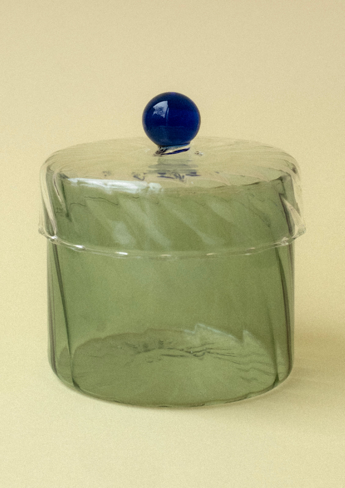 A green tinted glass jar with blue knob on lid.