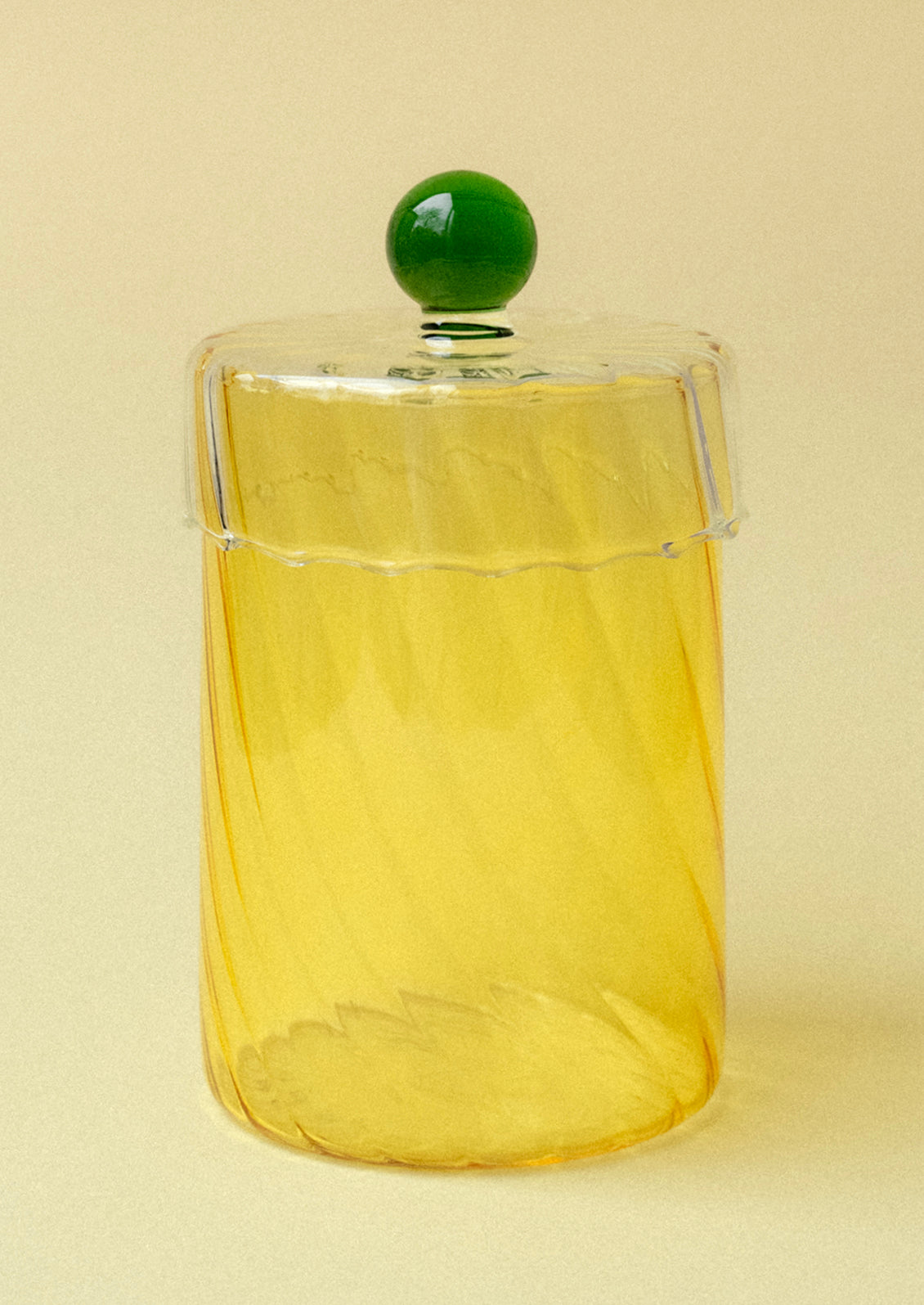 A yellow tinted glass jar with green knob on lid.