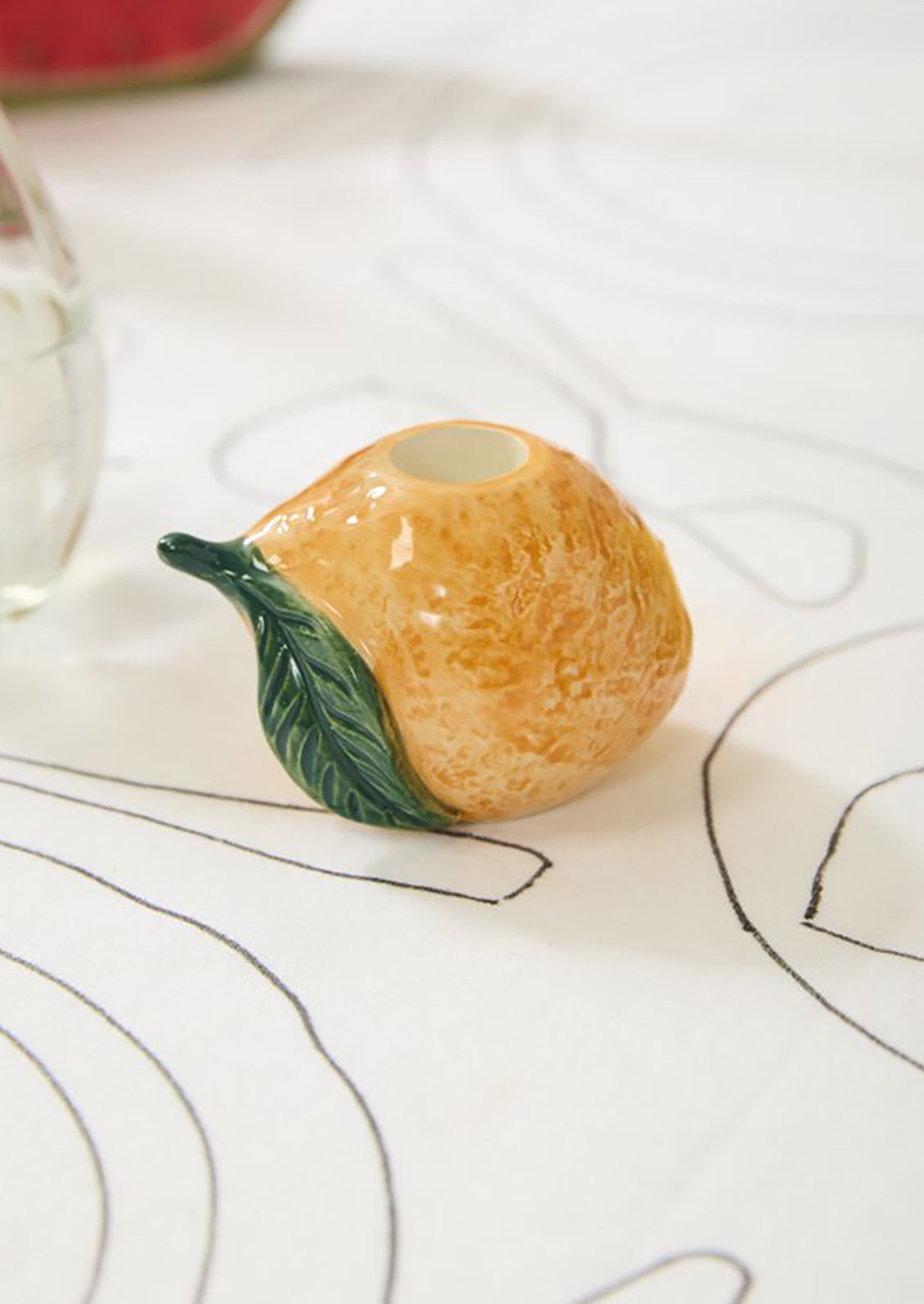 A ceramic candleholder in the shape of an orange.