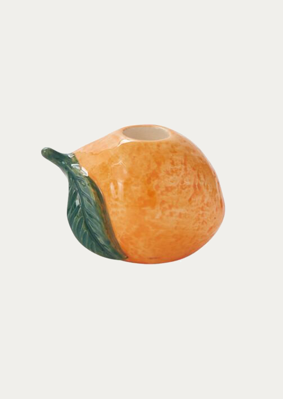 A ceramic candleholder in the shape of an orange.