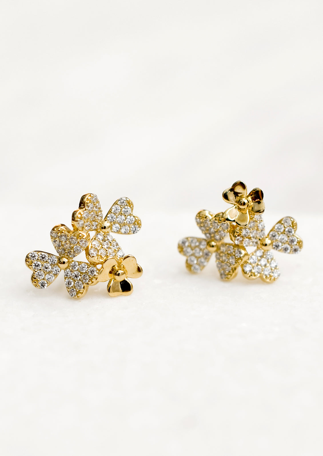 Gold stud earrings in shape of three flower cluster with clear crystals.