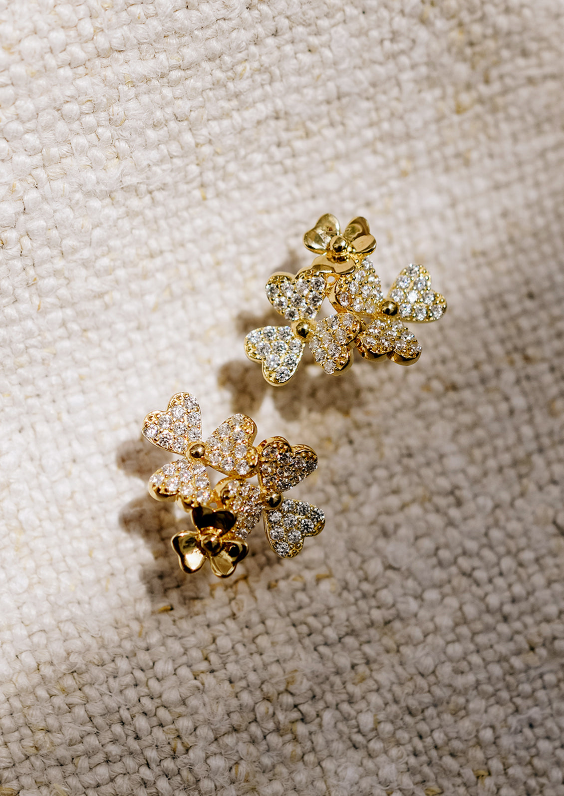 Gold stud earrings in shape of three flower cluster with clear crystals.