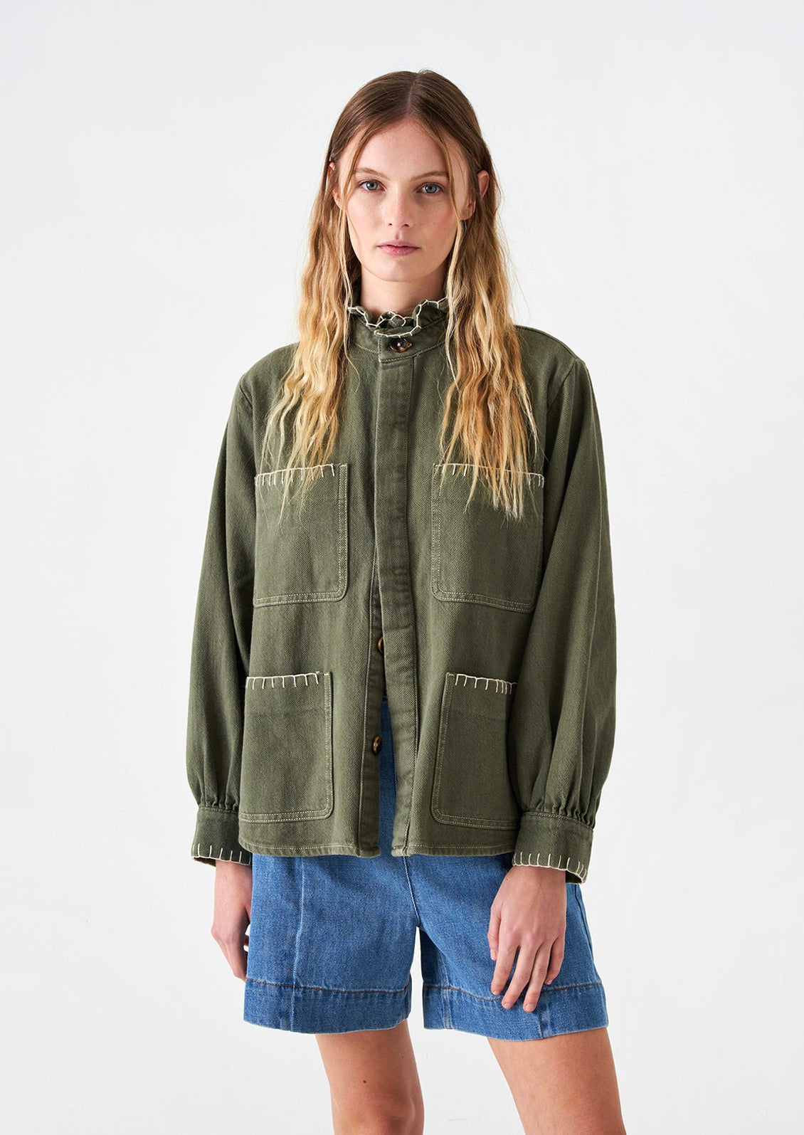 Woman wearing khaki green cotton jacket and denim shorts. 