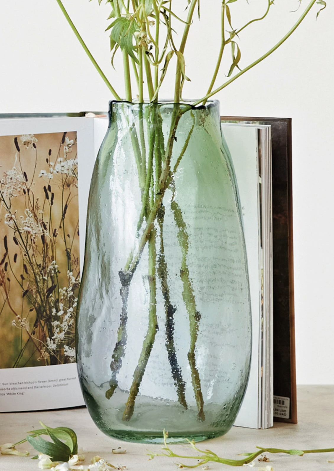 An asymmetrical glass vase in recycled green tinted glass with bubbles.