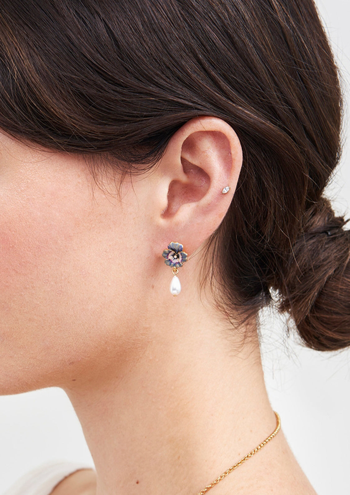 A pair of violet pansy flower earrings with a faux pearl drop.