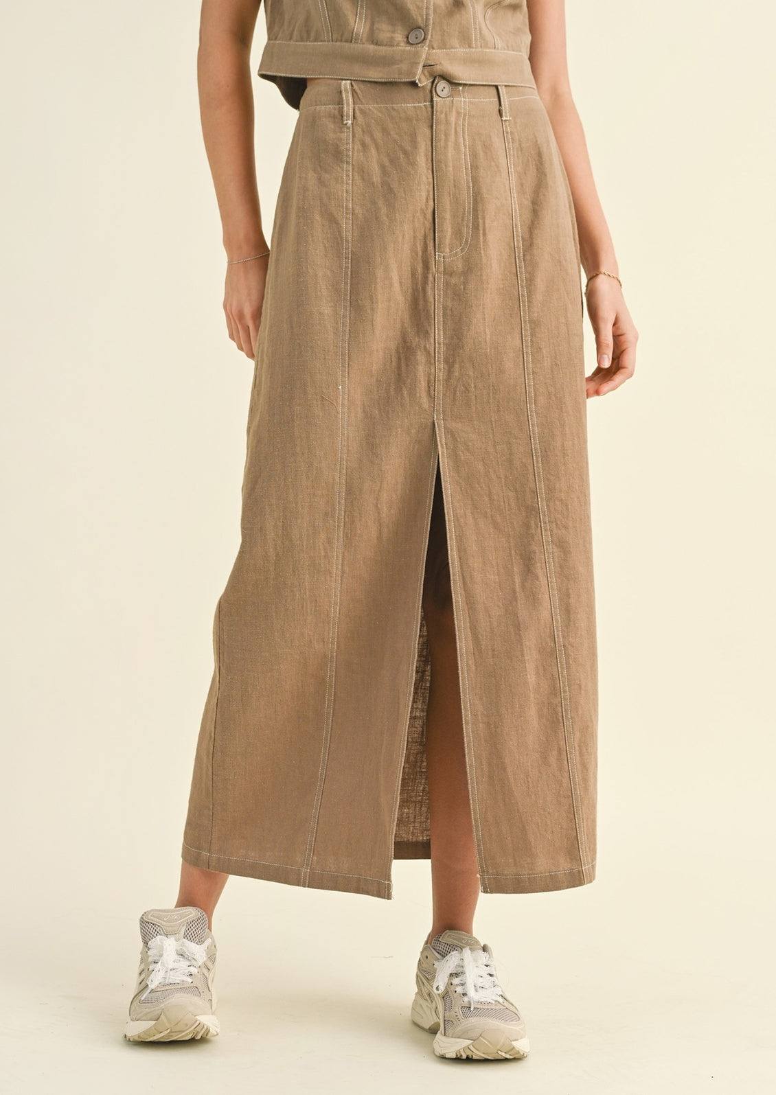 Woman wearing tan cotton midi skirt and sneakers. 