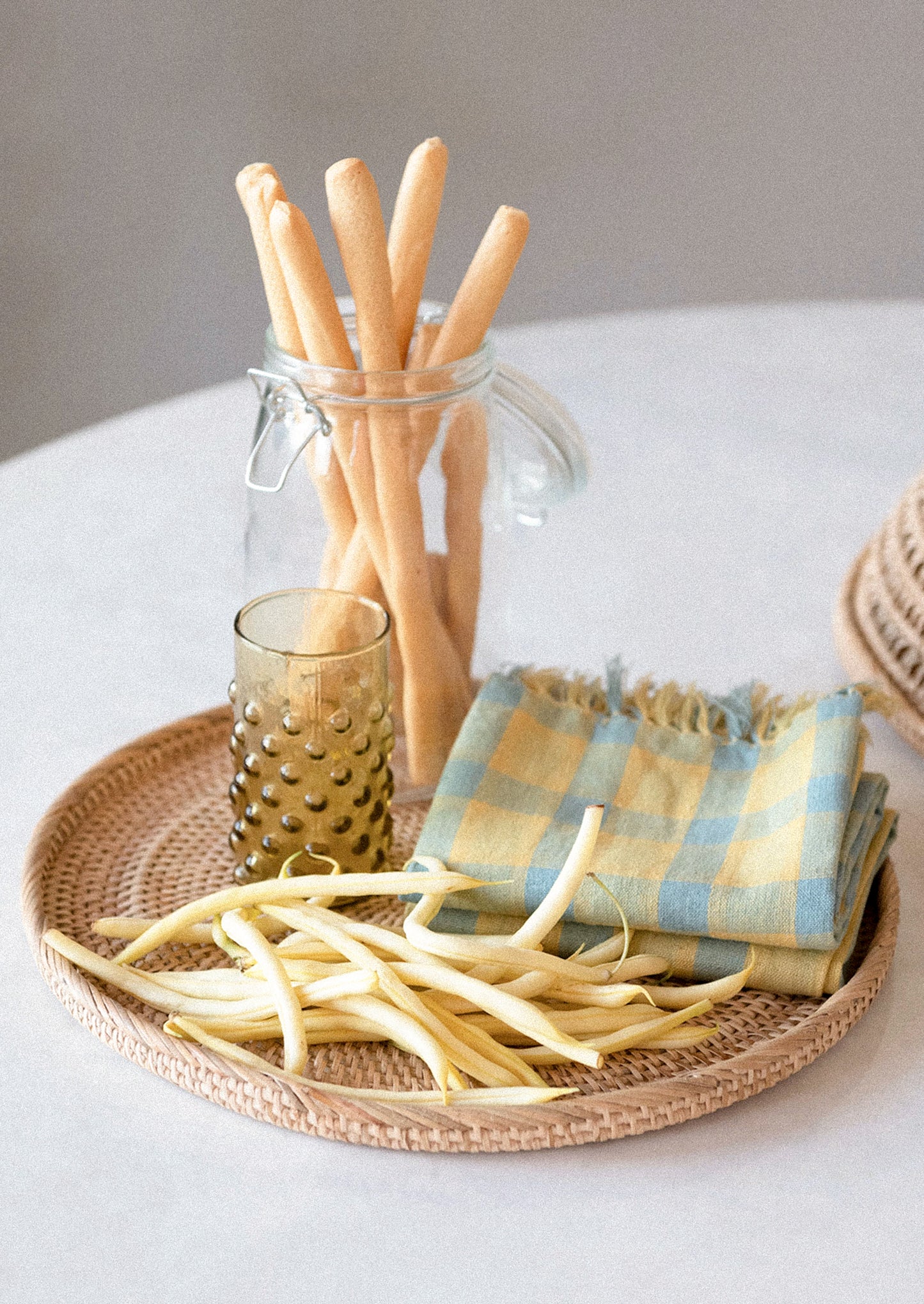 A cotton-linen tea towel in blue and yellow check pattern with tassel trim.