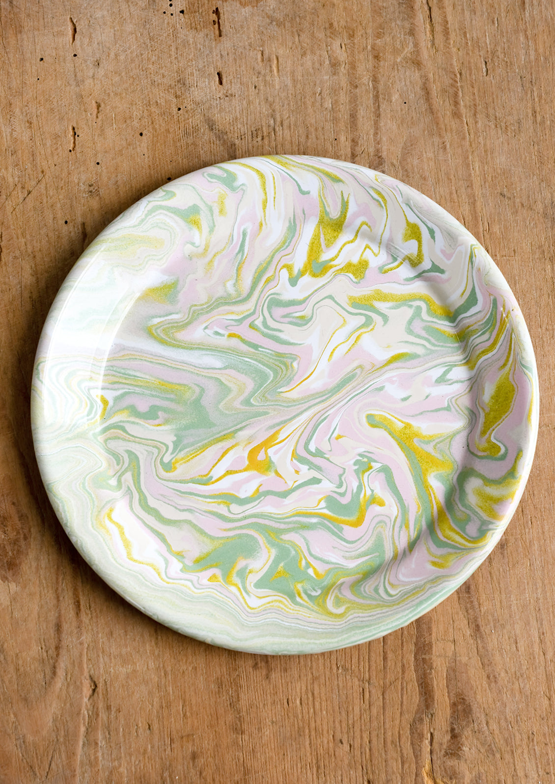 A round enamel plate with swirl pattern in pastel hues.