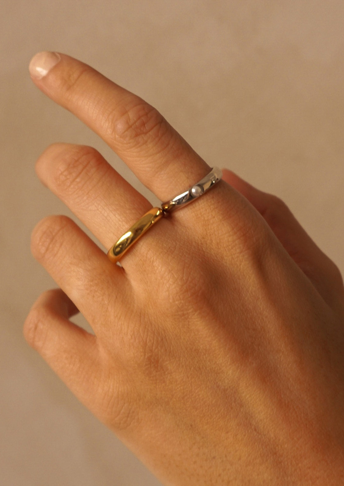 A silver ring with single inset pearl detail.