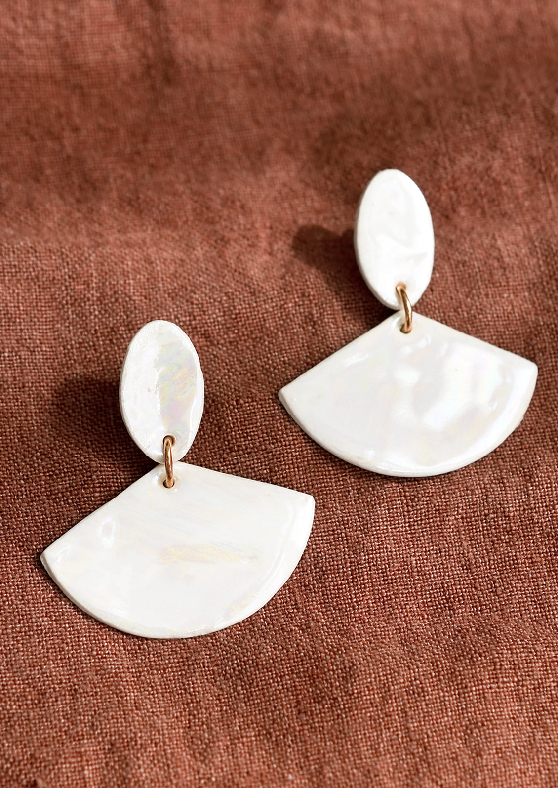 A pair of post back two-piece ceramic earrings in white pearl finish.