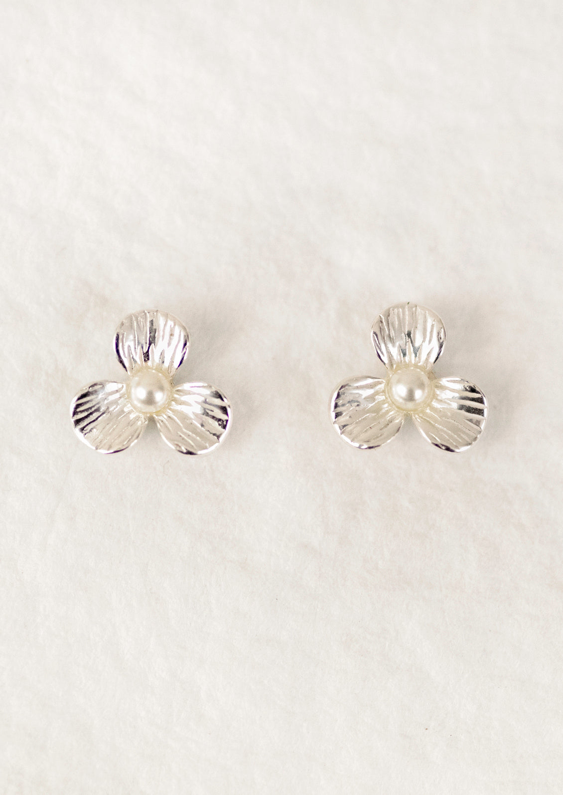 A pair of sterling silver 3-petal flower studs with a pearl center.