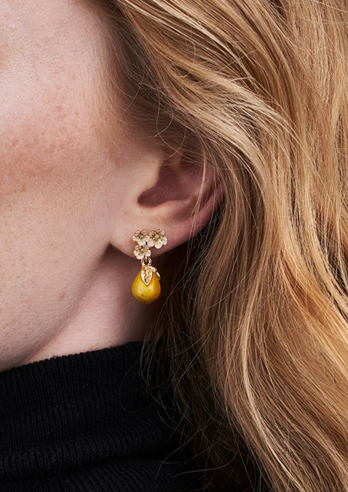 A pair of golden pear drop earrings adorned with light pink flowers.