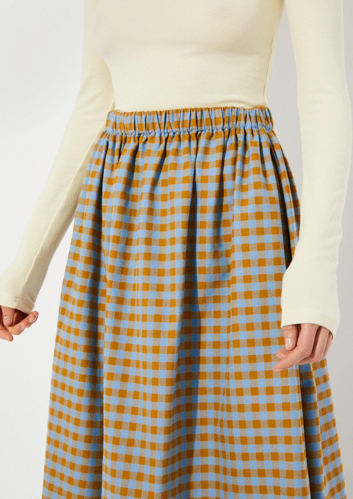 A woman wearing a gingham skirt in blue and brown.