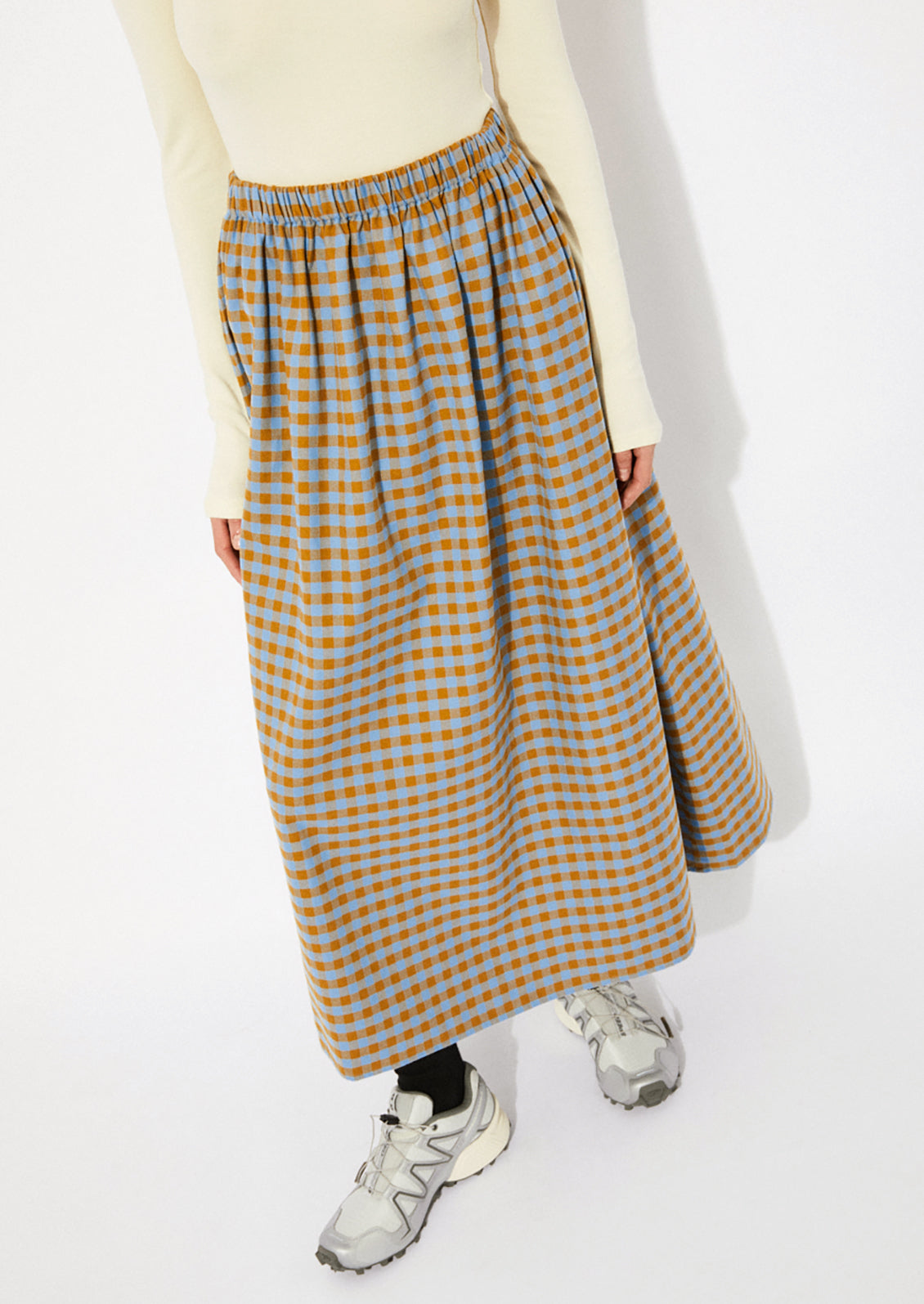 A woman wearing a gingham skirt in blue and brown.