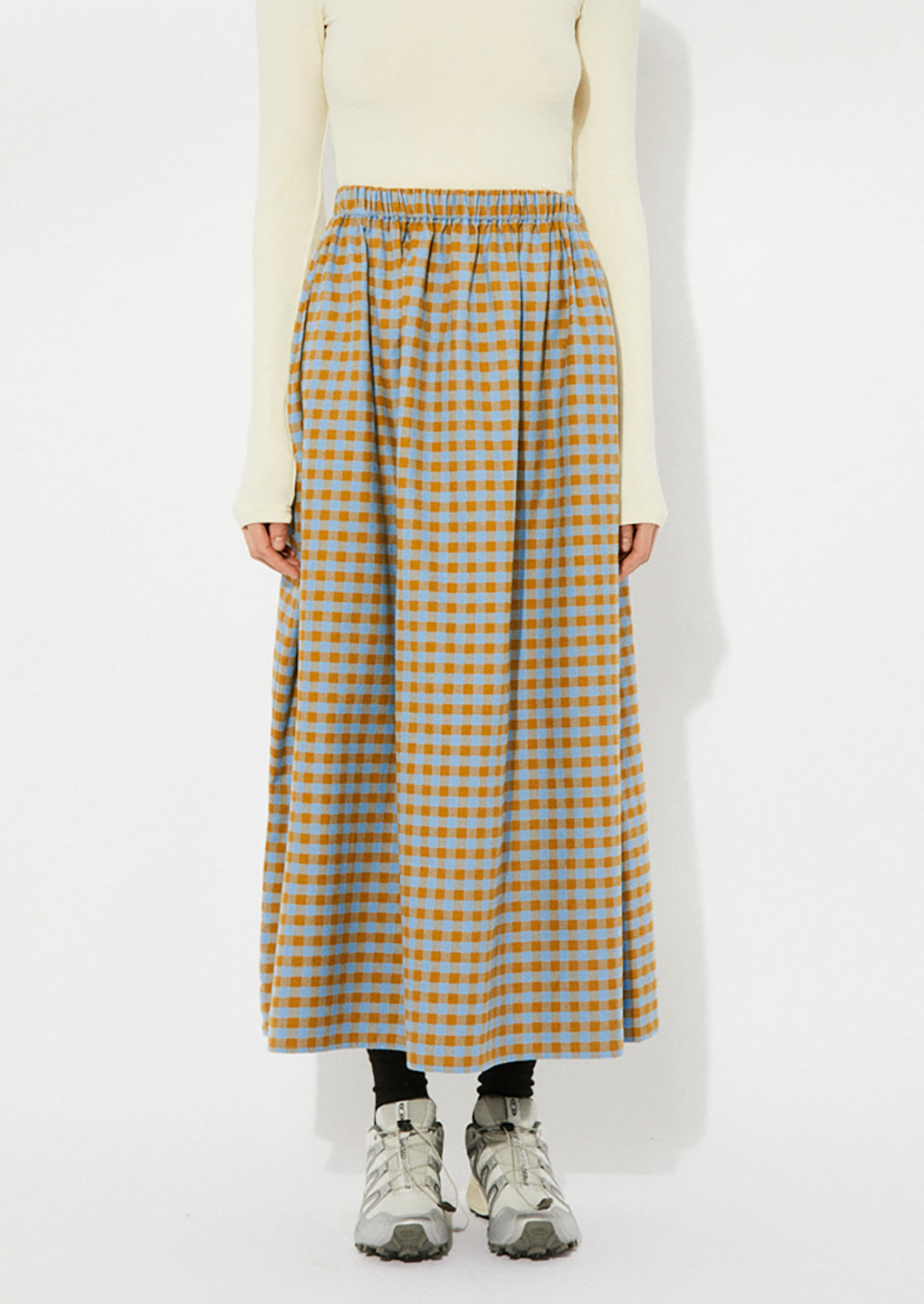 A woman wearing a gingham skirt in blue and brown.