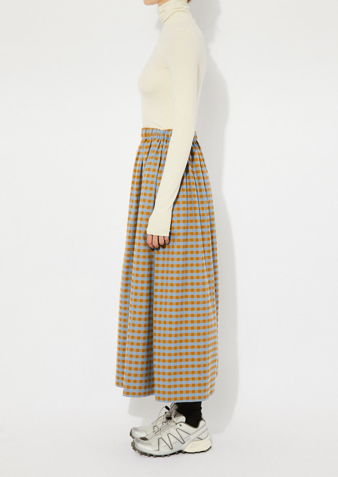 A woman wearing a gingham skirt in blue and brown.