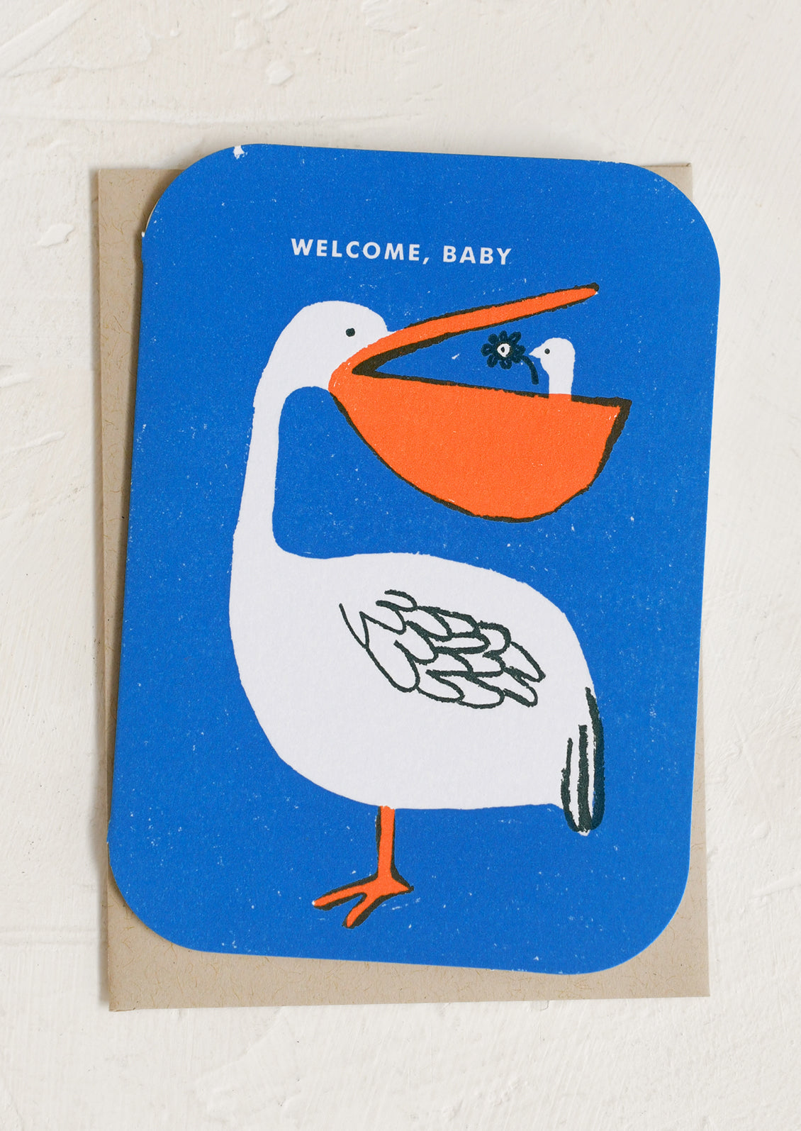 A blue greeting card with illustration of pelican with baby pelican in its beak, text reads "Welcome, baby".