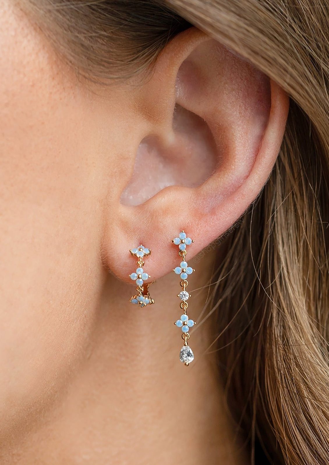 A person wearing periwinkle floral dangle earrings.